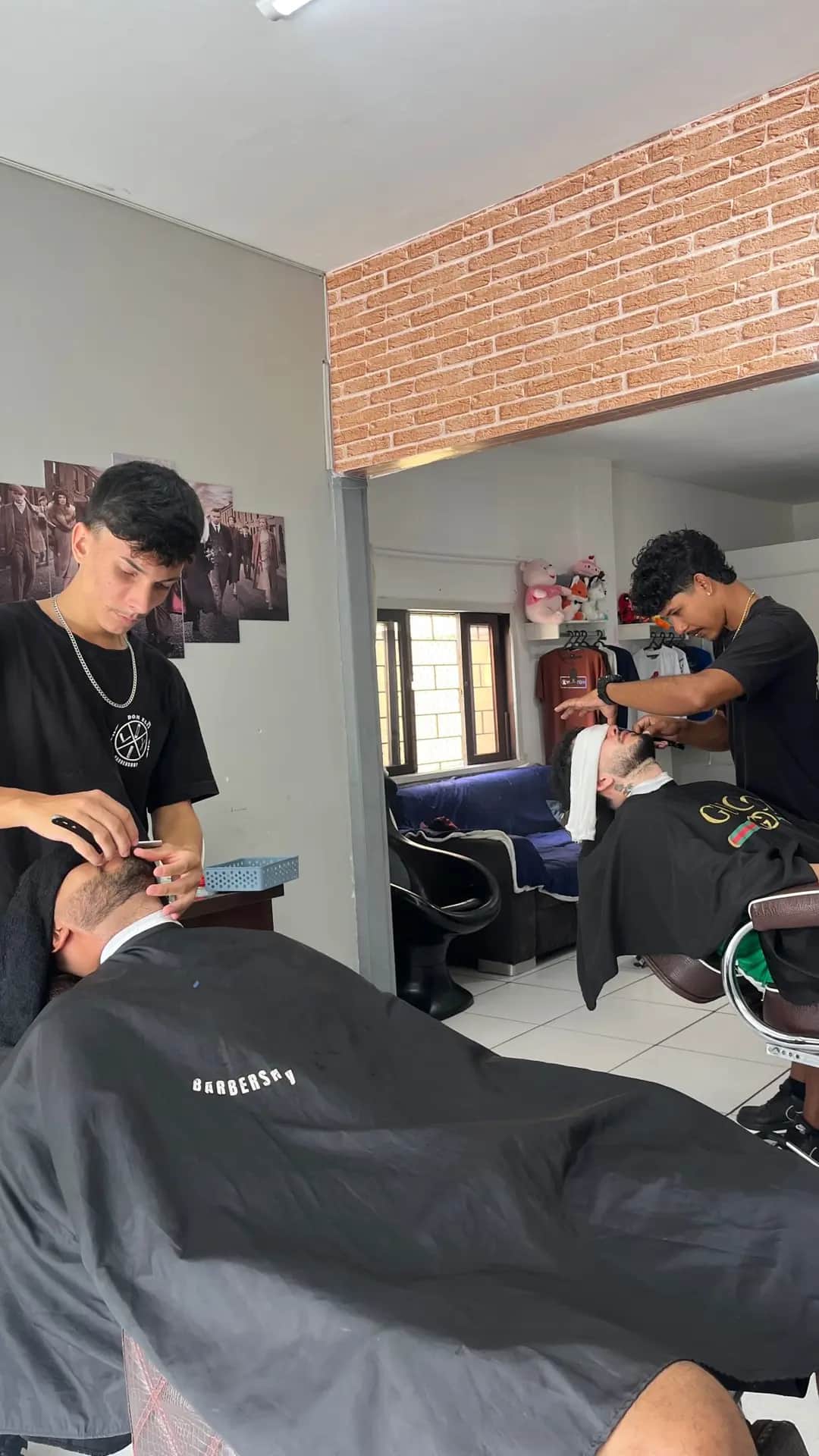 Dois barbeiros atendendo ao mesmo tempo no salão da Dom Elii Barbershop, em Curitiba