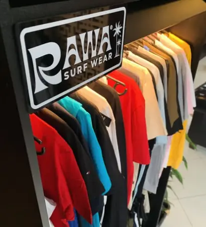 Araras com camisetas da Rawa Surf Wear na loja da Dom Elii Barbershop